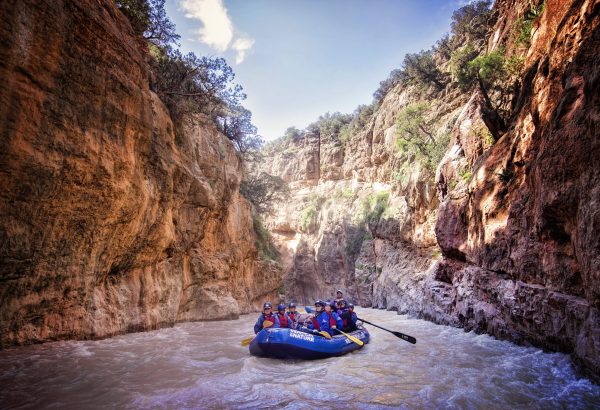 Raft travelling through river gorge in Morocco with guests
