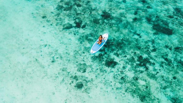 A guest paddleboarding over coral reefs in French Polynesia at sunrise
