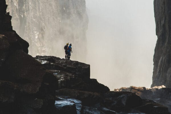 Two rafters standing below Victoria Falls