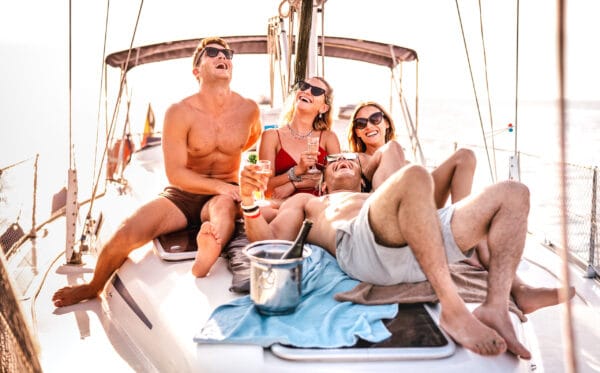 Guests relaxing on the deck of a sailboat anchored in a turquoise bay in French Polynesia